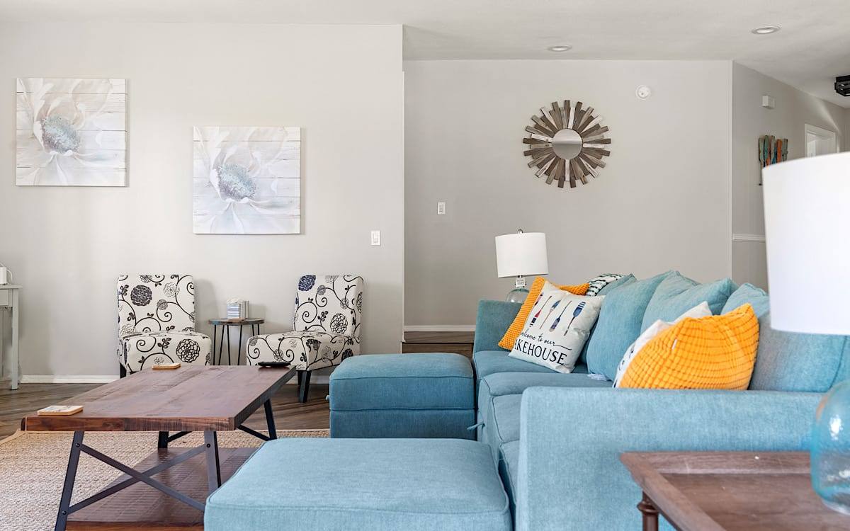 Bright living room with a teal sectional sofa, orange cushions and a wooden coffee table